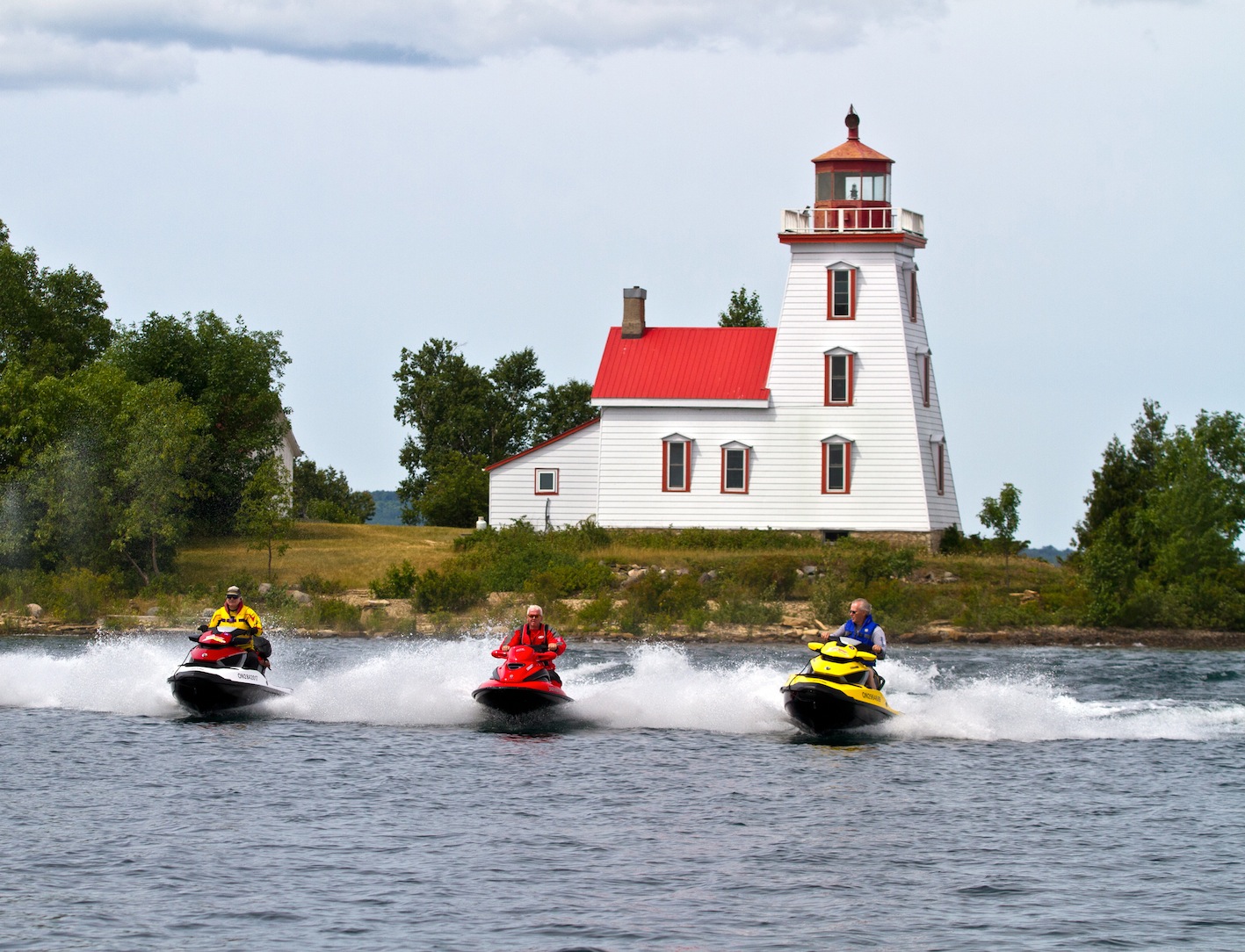 Three riders pass a lighthouse on the North Channel Sea Doo tour